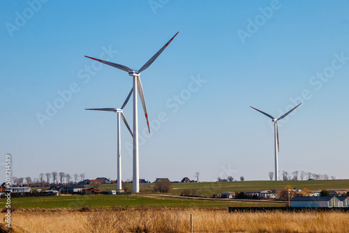 Wind turbines in a village. Renewable energy © olyasolodenko