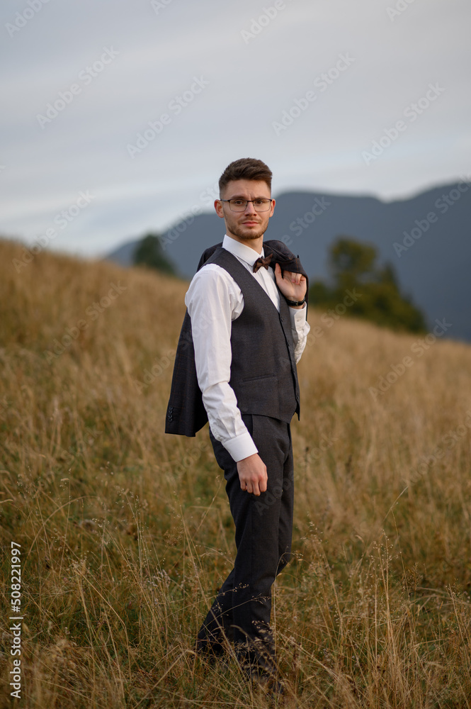 The groom is walking alone on the background of autumn mountains.