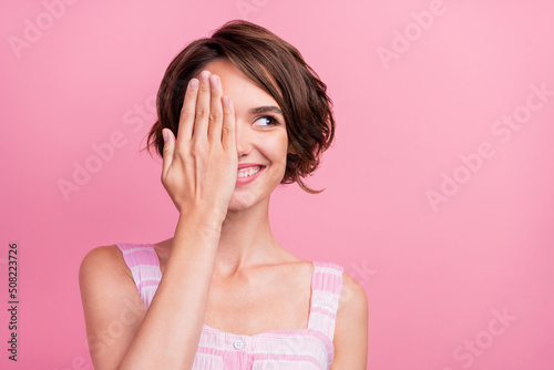 Photo of young cheerful girl close eye hand wondered look empty space eyesight correction isolated over pink color background