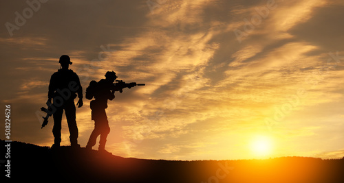 Silhouettes of soldiers standing against the backdrop of a sunset. Greeting card for Veterans Day, Memorial Day, Independence Day. USA celebration. Concept - patriotism, protection, remember honor.