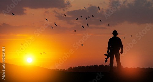 Silhouette of soldier standing against the backdrop of a sunset. Greeting card for Veterans Day, Memorial Day, Independence Day. USA celebration. Concept - patriotism, protection, remember honor. © hamara