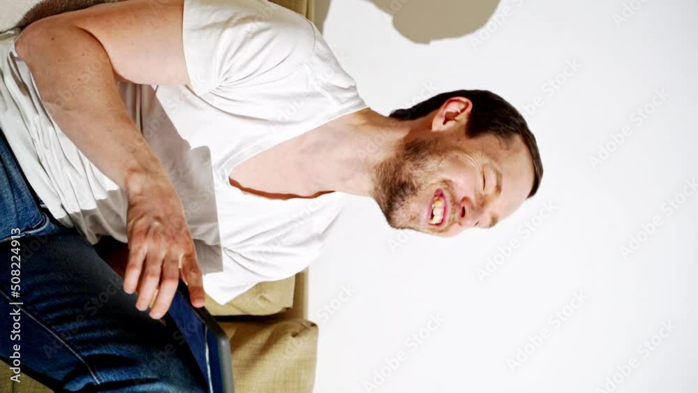 Young man working at living room. Home vacation sofa portrait. Blogger video. Alone in interior. Happy emotion. Smiling male person. Lifestyle action. House light background. Vertical video Young man working at living room. Home vacation sofa portrait. Blogger video. Alone in interior. Happy emotion. Smiling male person. Lifestyle action. House light background. Vertical video