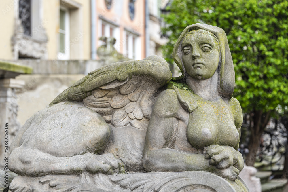 Sphinx sculpture, a fusion of a lion and a woman made from stone on the street of Old Town in Gdansk, Poland. Mysterious woman sphinx statue lies near old building in the park