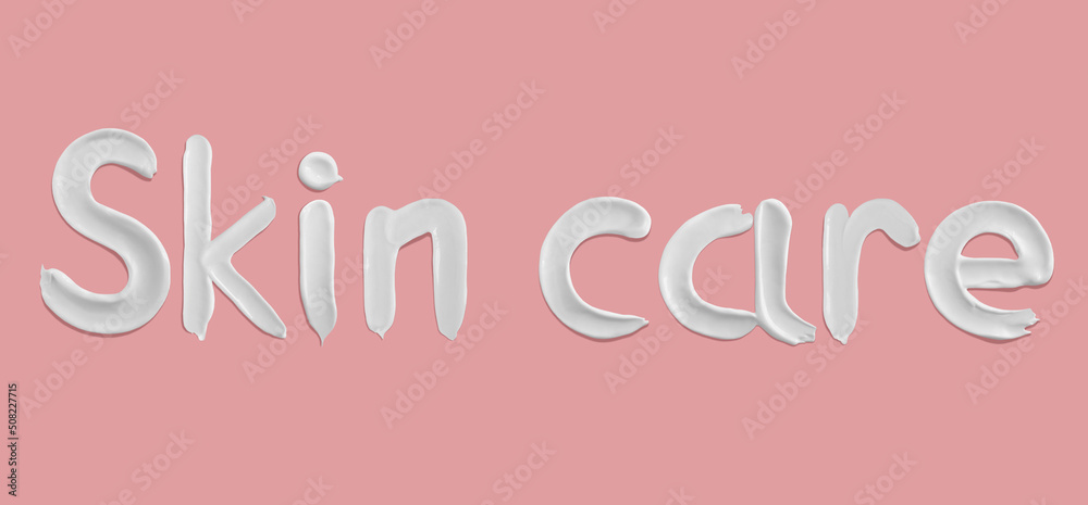 Skin care word written with cream texture smears on pink background