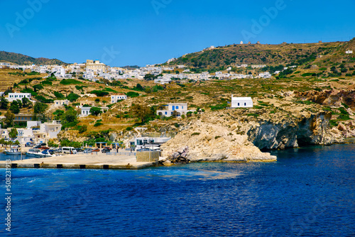 Beautiful summer day of Greek island town by seafront. Whitewashed houses by waterfront. Mediterranean vacations. Milos, Cyclades, Greece.