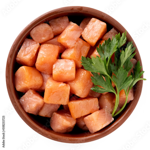 Salmon cut into small cubes in a bowl isolated on a white background, top view