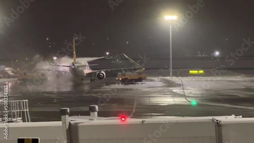 Deicing Airplane previous flight on cold winter night. Airport staff preparing plane with anti frost material on tail wing surface of aircraft.  High angle view from Airport window. 4K resolution photo