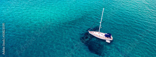 Foto Aerial view of anchored sailing yacht in emerald sea