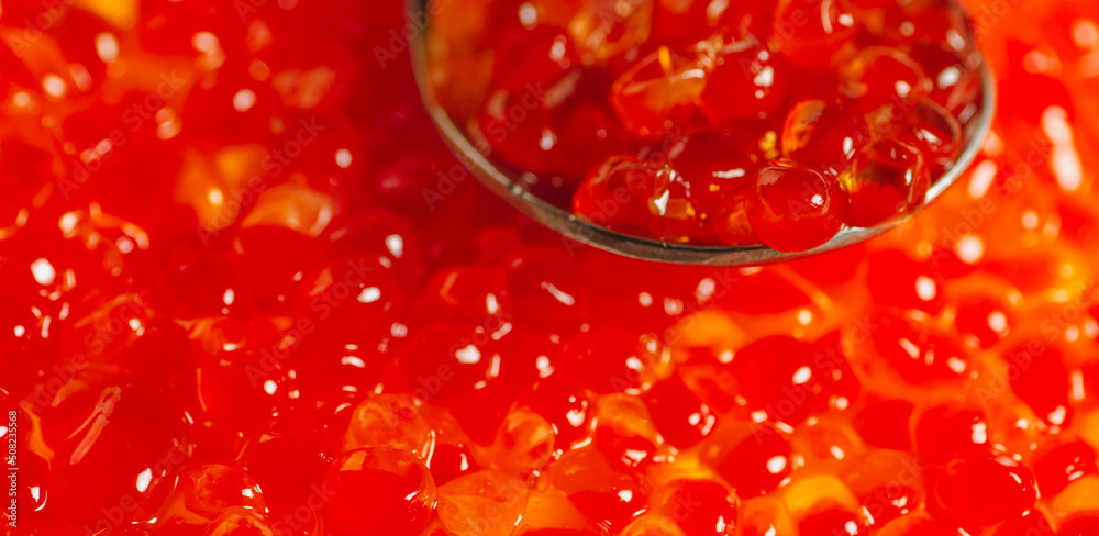 Teaspoon with juicy red caviar on background of caviar. Salmon caviar grainy. Close up. Teaspoon with juicy red caviar on background of caviar. Salmon caviar grainy. Close up.