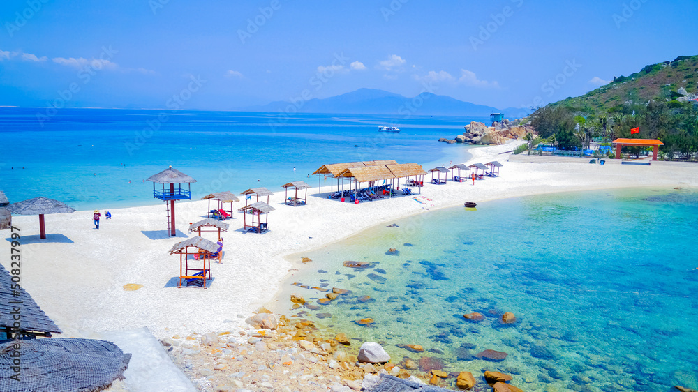 Fototapeta premium Double beach in the sea on the islands. Sunny day, turquoise transparent sea. A spit between two small islands. Lifeguard tower and beach gazebos. 