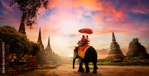 The tourists on an ride elephant tour of "Ayuthaya" the ancient city of Thailand in sunset background. © sippakorn