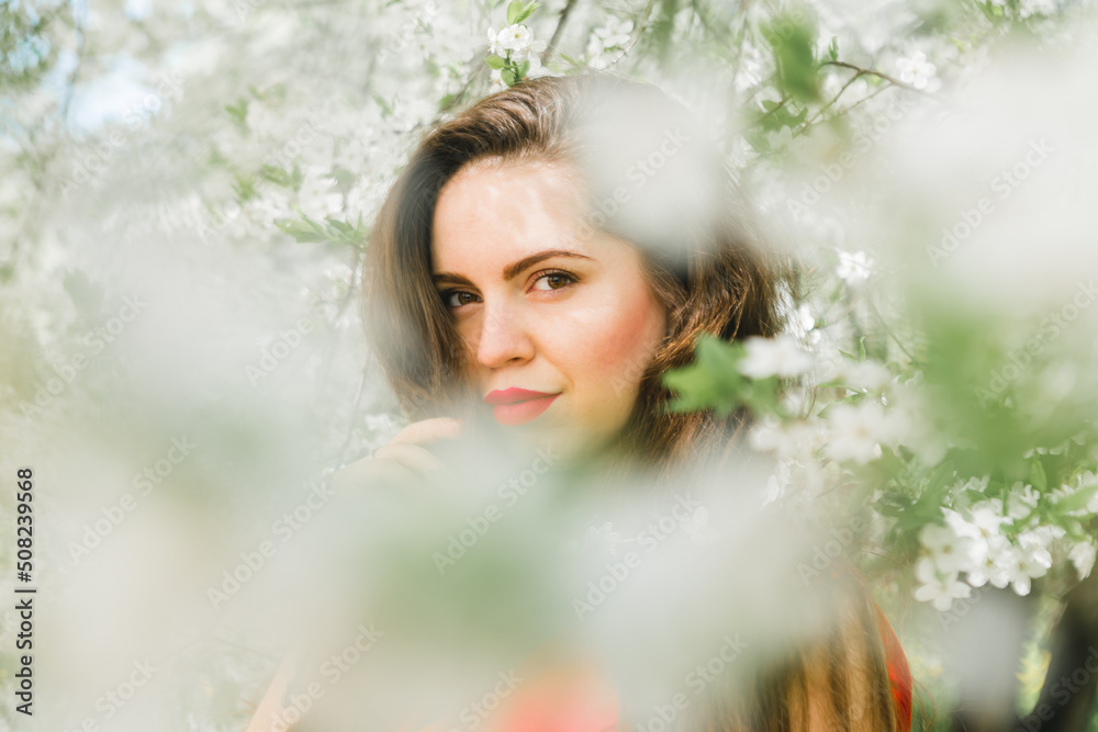 portrait of a beautiful young girl with red lips and a red dress in blooming garden portrait of a beautiful young girl with red lips and a red dress in blooming garden