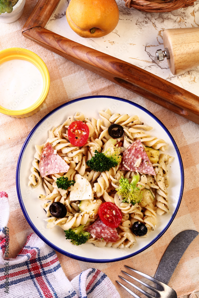 Pasta salad with tomatoes, ham, black olives, broccoli and cheese
