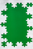 Framing in the form of a rectangle, made of a white jigsaw puzzle. Frame text and jigsaw puzzles. Frame made of jigsaw puzzle pieces on green background.