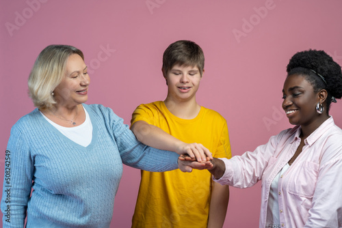 Guy and two women touching with outstretched hands photo
