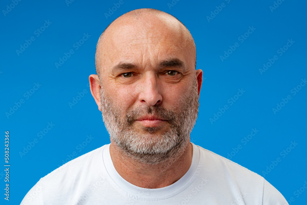 Fototapeta premium Portrait of a middle-aged man against blue background in studio