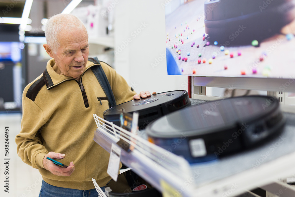 senor man pensioner buying Robotic vacuum cleaner in showroom of electrical appliance store senor man pensioner buying Robotic vacuum cleaner in showroom of electrical appliance store