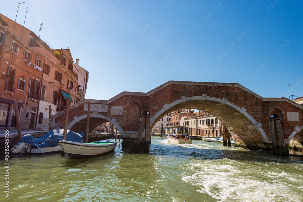Naklejka premium Venice downtown. Bridge of the Three Arches (Ponte dei Tre Archi or di San Giobbe), 1688, made of brick and stone, over the Cannaregio canal of the Venetian lagoon. Veneto, Italy, Europe. 