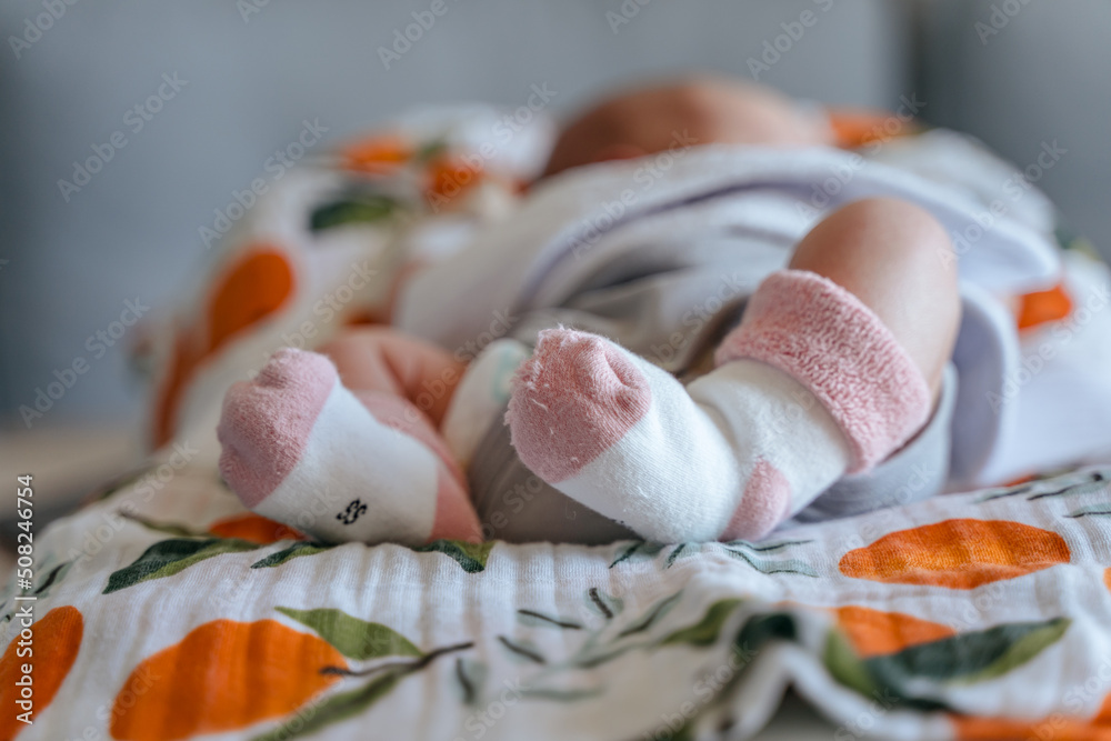 Socks on the legs of a newborn baby, the first day at home after the maternity hospital, focus on the legs