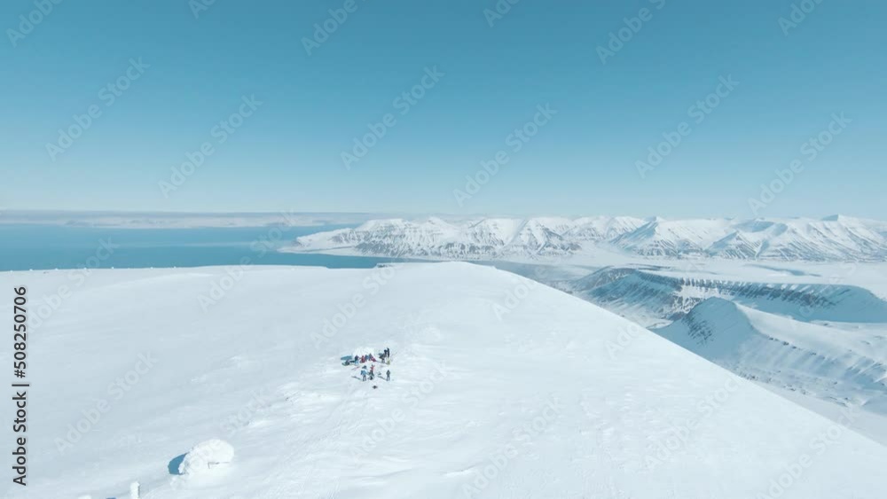 Team of hikers reaching snowy mountain top in majestic landscape of Svalbard Team of hikers reaching snowy mountain top in majestic landscape of Svalbard