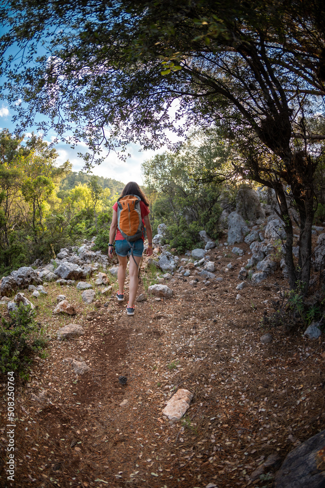 A girl with a backpack walks along a mountain road A girl with a backpack walks along a mountain road