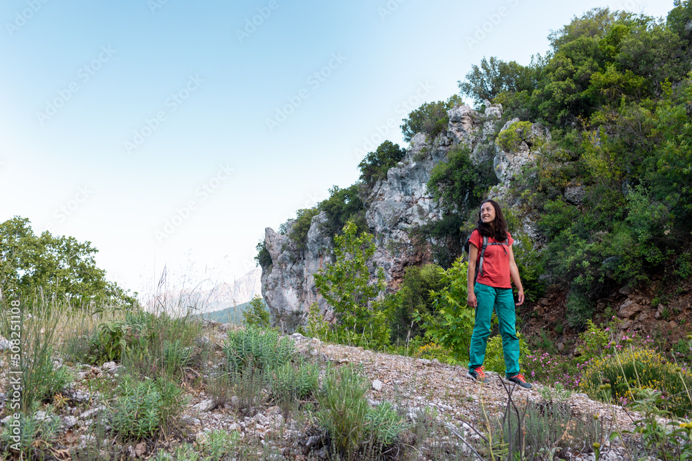 A young woman with a backpack looks at the valley