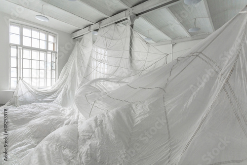 Art installation with a white parachute hanging in the huge white photo studio.