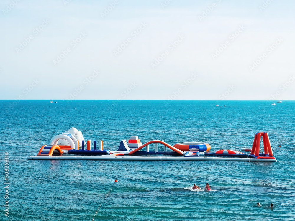 A bright inflatable aqua park is located in the middle of the blue sea on a sunny summer day. Southern Sea Activities