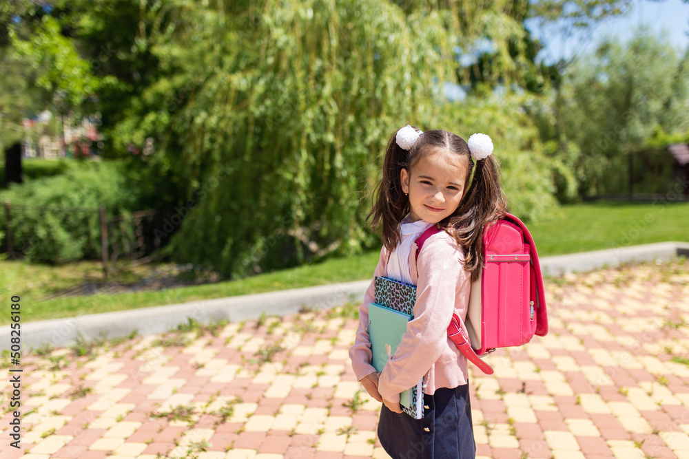 Smiling little cute schoolgirl in uniform with school bag, backpack, back to school, 1 september