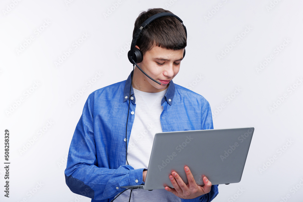 Young teenage boy using his laptop , finishing his schoolwork or listening to an online class Young teenage boy using his laptop , finishing his schoolwork or listening to an online class