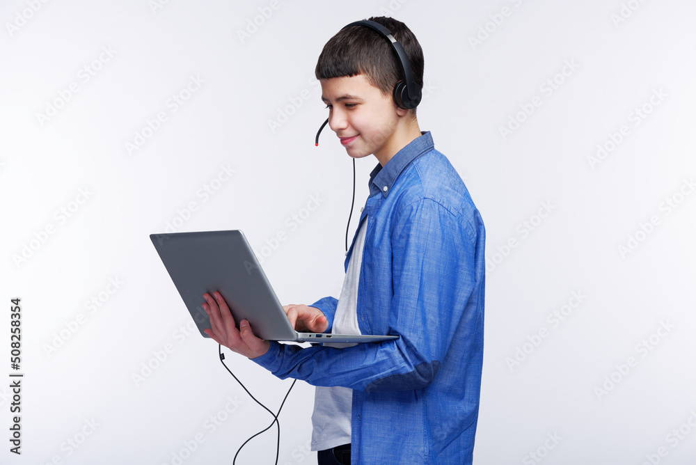 Young teenage boy using his laptop , finishing his schoolwork or listening to an online class Young teenage boy using his laptop , finishing his schoolwork or listening to an online class