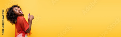 laughing african american woman showing thumbs up isolated on yellow, banner.