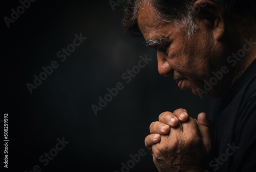 Tablou canvas Elderly Asian man prayer to god on a black background