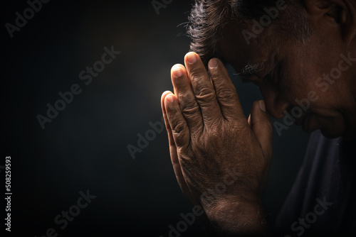 Valokuvatapetti Elderly Asian man bowed his head praying to God on a black background at home