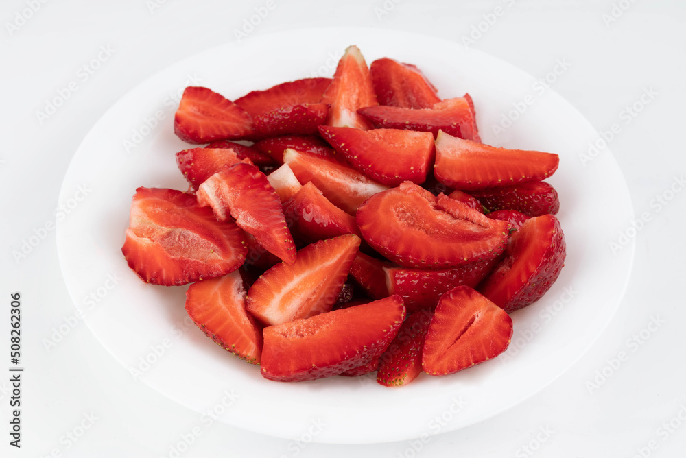 Ripe strawberries in slices on a white plate.Useful berries. Ripe strawberries in slices on a white plate.Useful berries.