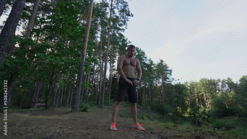 adult person with bare torso tilts forward in forest glade outdoors adult person with bare torso tilts forward in forest glade outdoors