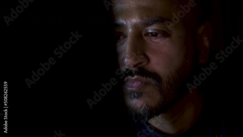 Close up view of a young Asian man using computer for internet, reading, watching, working online late. photo