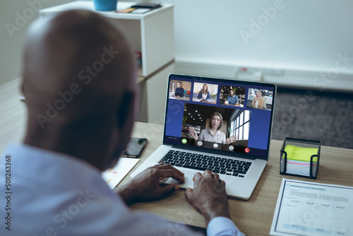 African american businessman video conferencing with multiracial coworkers while working on laptop