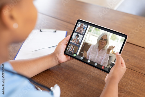 Multiracial business coworkers having online meeting through digital tablet in office