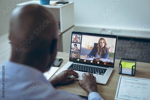 African american businessman discussing work with colleagues in online meeting through laptop