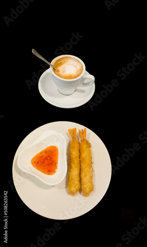 two battered prawns to eat with sweet and sour sauce, and a cup of coffee latte