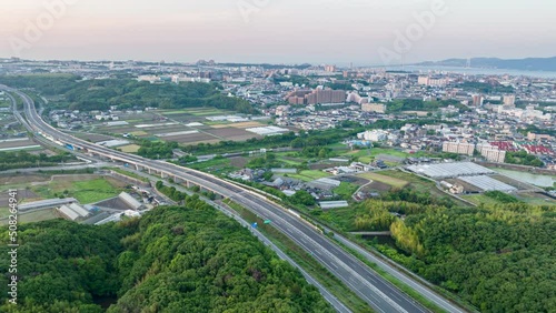 View of highway through rice fields and green hills with sprawling town in background