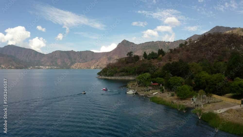 A blue river surrounded by mountains from which many speed boats are going. There is a variety of greenery all around and a beautiful view is created after the sun rises on the hill A blue river surrounded by mountains from which many speed boats are going. There is a variety of greenery all around and a beautiful view is created after the sun rises on the hill