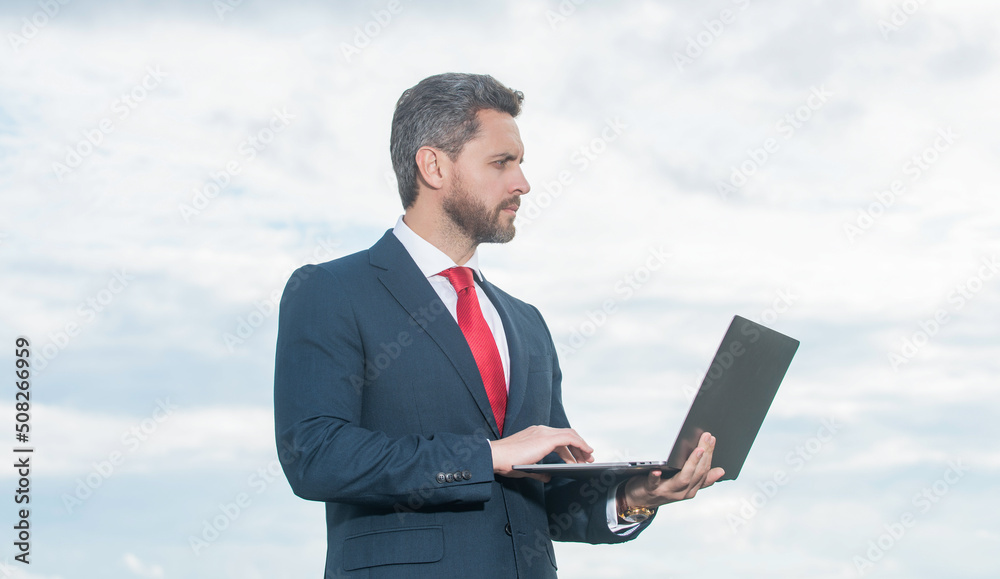 ceo in suit using laptop on sky background ceo in suit using laptop on sky background