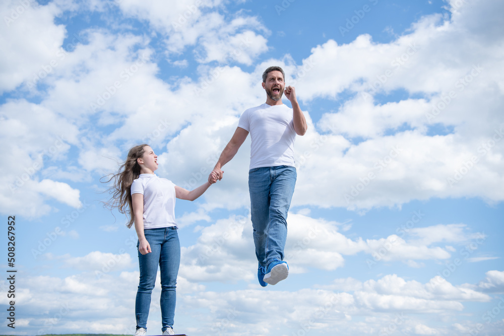 daughter hold her inspired father jumping in sky daughter hold her inspired father jumping in sky