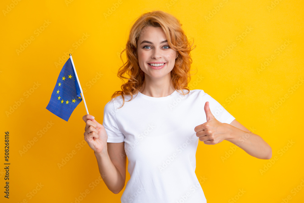 Portrait of friendly pretty woman holding flag of European Union, symbol of Europe, EU association and community. Studio isolated yellow background. Portrait of friendly pretty woman holding flag of European Union, symbol of Europe, EU association and community. Studio isolated yellow background.