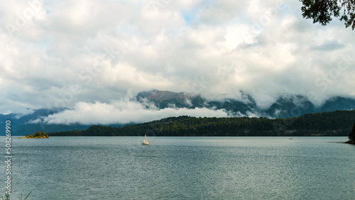 Obraz na płótnie Barco velero navegando un lago calmo con nubes bajas y montañas de fondo. Villa La Angostura, Argentina w salonie