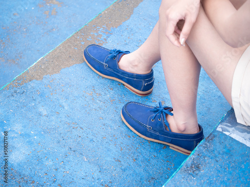 Female fashion in boat shoes leather, Close up view on woman's legs in gray jeans and navy blue shoes leather.