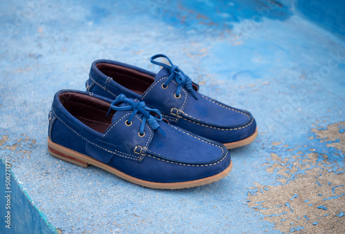 Men fashion navy blue leather boat shoes on blue floor background.