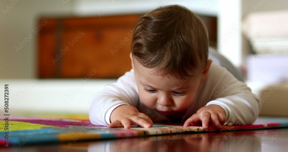 Cute baby lying on floor touching play carpet Cute baby lying on floor touching play carpet